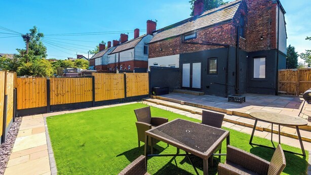 A residential backyard with a patio, a lawn, and a wooden fence.