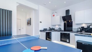 A modern kitchen with a ping pong table, a microwave, and a coffee maker.