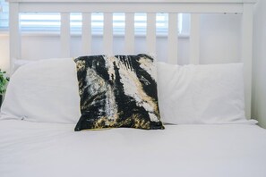 A bed with white bedding and a single black and white pillow. - Modern Home for 9 with Garden (Greater Manchester)
