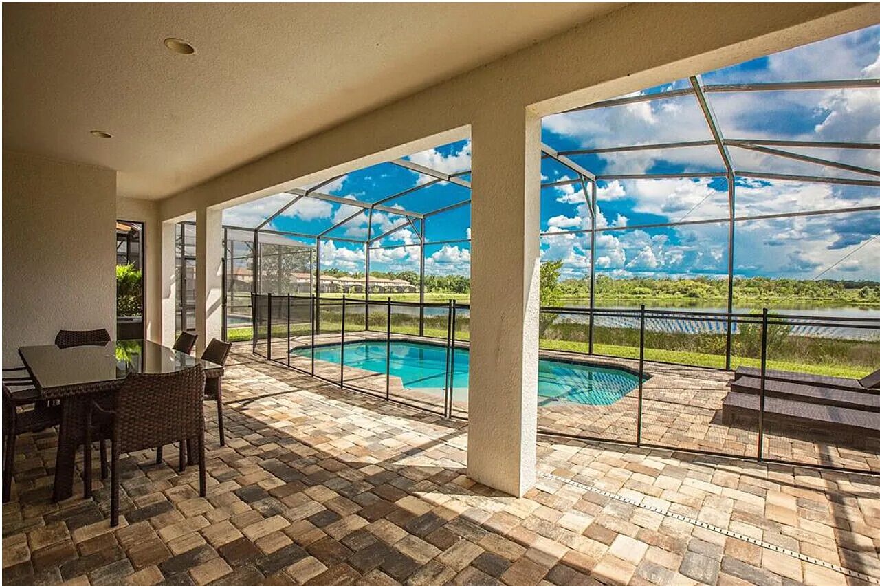 A covered patio with a pool, outdoor seating, and a view of the landscape.