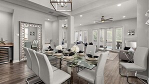 A spacious dining area with a glass table, white chairs, and a ceiling fan. - Reflections Manor at Reunion | Stay in style at 5-bedroom villa in Orlando Near Disney (Kissimmee)
