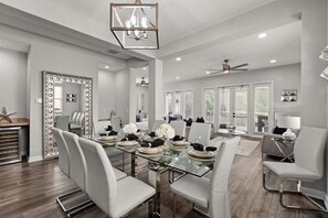 A spacious dining area with a glass table, white chairs, and a ceiling fan. - Reflections Manor at Reunion | Stay in style at 5-bedroom villa in Orlando Near Disney (Kissimmee)