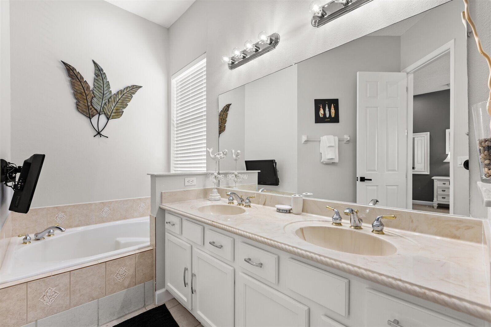 A bathroom with two sinks, a large mirror, and decorative wall art.