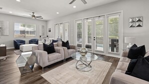 A spacious living room with a modern sofa set, a glass coffee table, and a ceiling fan. - Reflections Manor at Reunion | Stay in style at 5-bedroom villa in Orlando Near Disney (Kissimmee)