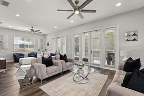 A spacious living room with a modern sofa set, a glass coffee table, and a ceiling fan. - Reflections Manor at Reunion | Stay in style at 5-bedroom villa in Orlando Near Disney (Kissimmee)