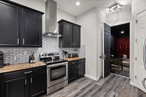 A modern kitchen with dark cabinetry, a stainless steel stove, and a brick backsplash. - Reflections Manor at Reunion | Stay in style at 5-bedroom villa in Orlando Near Disney (Kissimmee)