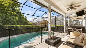 A covered outdoor area with a pool, seating, and a patio. - Reflections Manor at Reunion | Stay in style at 5-bedroom villa in Orlando Near Disney (Kissimmee)
