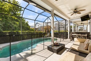 A covered outdoor area with a pool, seating, and a patio. - Reflections Manor at Reunion | Stay in style at 5-bedroom villa in Orlando Near Disney (Kissimmee)