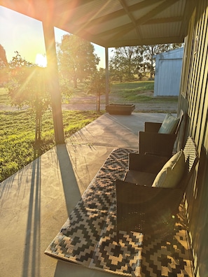 A covered outdoor seating area with a patterned rug, a bench, and a small table.