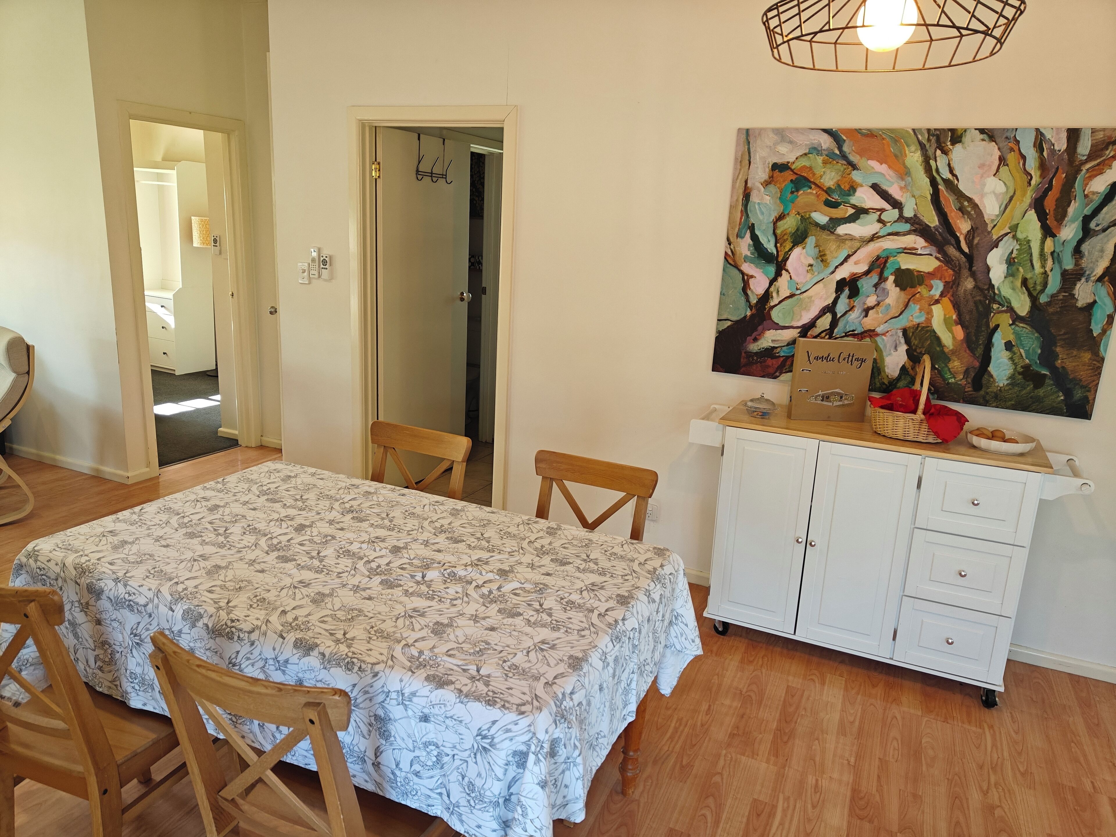 Een eethoek met een tafel, stoelen, een kast en een schilderij aan de muur.