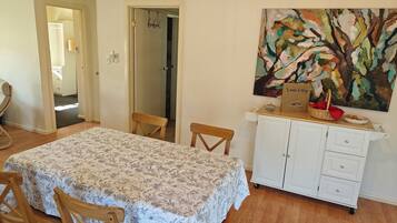 Een eethoek met een tafel, stoelen, een kast en een schilderij aan de muur.