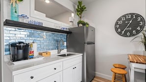 Eine moderne Küche mit Kühlschrank, Spüle und einer Uhr an der Wand.