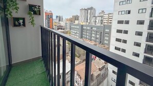 Een balkon met uitzicht op een stadsgezicht, met meerdere gebouwen en een heldere lucht.