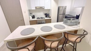 Een kleine keuken met een centraal eiland, vier barkrukken en een koelkast.