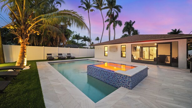 A swimming pool with a tiled hot tub, surrounded by palm trees and a white fence. - Naples Paradise - Heated Saltwater Pool/Spa, Walk/Bike to the Beach! (Naples)
