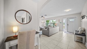 A modern living room with a sofa, a coffee table, a round mirror, and a lamp. - Naples Paradise - Heated Saltwater Pool/Spa, Walk/Bike to the Beach! (Naples)
