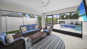 An outdoor patio with wicker furniture, a ceiling fan, and a view of a swimming pool. - Naples Paradise - Heated Saltwater Pool/Spa, Walk/Bike to the Beach! (Naples)