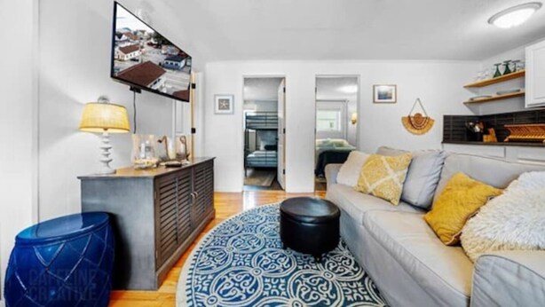 A modern living room with a sofa, a patterned rug, a coffee table, a lamp, and a television. - 70 E Grand OOB | 2BR Condo Steps to the Beach (Old Orchard Beach)