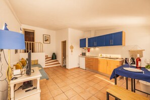 A compact living space with a kitchenette, a dining area, and a staircase leading to an upper level. - Comfortable one bedroom apartment with shared swimming pool (Fuseta)