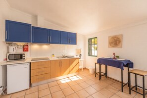 A compact kitchen with blue cabinets, a white refrigerator, a microwave, and a small sink. - Comfortable one bedroom apartment with shared swimming pool (Fuseta)