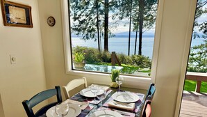 A dining table set for four with a view of a lake and trees. - NEW LISTING-Mutiny Bay Ebb Tide Cabin AMAZING SUNSETS, EAGLES GALORE SANDY BEACH (Freeland)