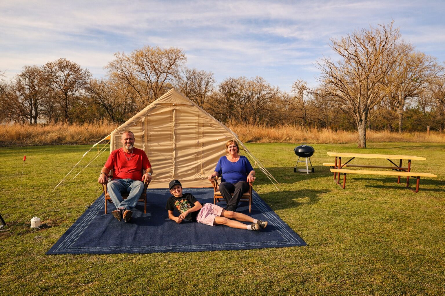 Une scène de camping avec une tente, une table de pique-nique et un champ d’herbe.