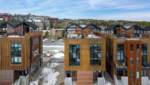 A modern multi-story building with large windows and balconies, surrounded by snow. - Downtown WP Loft 57 I Rooftop Hot Tub & Lounge I Great Views I Bunk Room I Discounted Attractions (Winter Park)