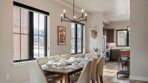 A dining area with a large table set for six, a chandelier, and a view of the kitchen. - Downtown WP Loft 57 I Rooftop Hot Tub & Lounge I Great Views I Bunk Room I Discounted Attractions (Winter Park)