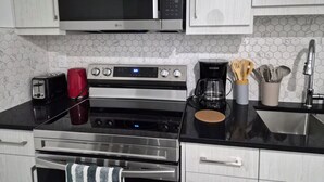 A modern kitchen with a microwave, toaster, coffee maker, and stainless steel appliances. - Quaint 2-bedroom house in Chestermere perfect for relaxing stays (Chestermere)