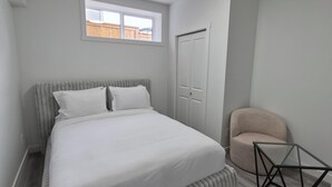 A bedroom with a bed, a window, a door, and a chair. - Quaint 2-bedroom house in Chestermere perfect for relaxing stays (Chestermere)