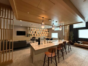 A modern interior with a central island, bar stools, a sofa, and a TV mounted on the wall. - Monthly 2BR Apartment in Koreatown with Gym, AC and Heat – Prime LA Location (Los Angeles)