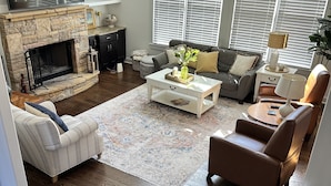 A living room with a stone fireplace, a sofa, a coffee table, and a lamp. - FIFA World CUP -Spacious 4 bedroom house with Pool Table and Gym (Marietta)