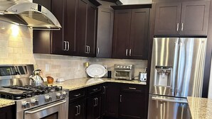 A modern kitchen with dark cabinetry, stainless steel appliances, and a herringbone wood floor. - FIFA World CUP -Spacious 4 bedroom house with Pool Table and Gym (Marietta)