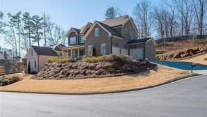 A suburban house with a driveway, a small pool, and a landscaped area with rocks. - FIFA World CUP -Spacious 4 bedroom house with Pool Table and Gym (Marietta)