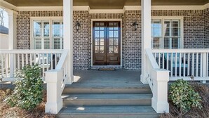 A brick house with a front porch, white railings, and a double door. - FIFA World CUP -Spacious 4 bedroom house with Pool Table and Gym (Marietta)