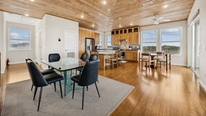 Une cuisine spacieuse dotée de meubles en bois, d’un îlot central et d’un coin repas avec une table et des chaises en verre.