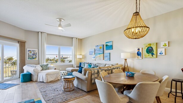 A spacious living room with a sofa, chairs, a dining table, and artwork on the walls. - Coastal Condo Oasis | Walk to Beach (Fernandina Beach)