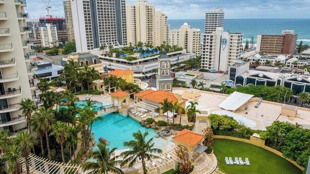 Un hôtel doté d’une piscine, de palmiers et offrant une vue sur l’océan.