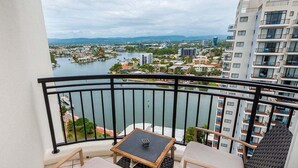 Un balcon donnant sur une rivière et des immeubles, aménagé avec une table et des chaises.