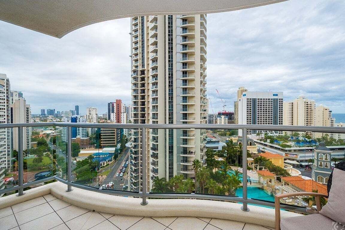 A high-rise building with balconies, a pool area, and a cityscape view.