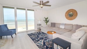 A living room with a sofa, armchair, coffee table, and a ceiling fan. - Sand Dollar 1-407 Amazing Oceanfront Views from Private Balcony! (St. Augustine)