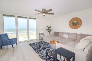 A living room with a sofa, armchair, coffee table, and a ceiling fan. - Sand Dollar 1-407 Amazing Oceanfront Views from Private Balcony! (St. Augustine)