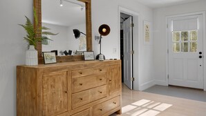 A wooden dresser with a large mirror, a potted plant, and decorative items.