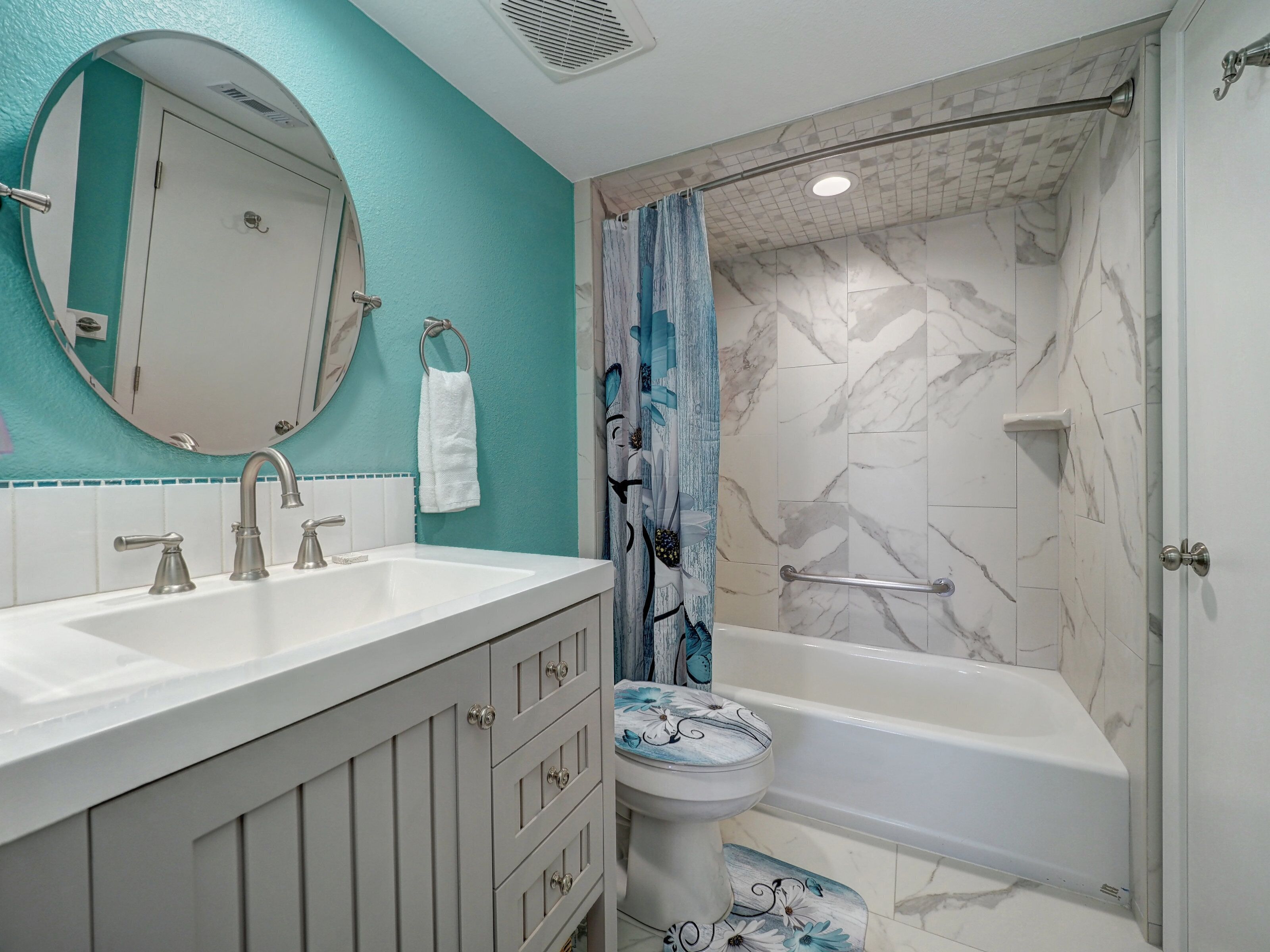Une salle de bain avec un double lavabo, des toilettes, une baignoire, un rideau de douche et un miroir.