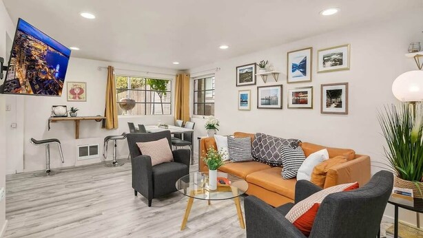 Una sala de estar moderna con un sofá, sillones, una mesa de centro y un televisor.