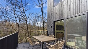Eine Holzterrasse mit Tisch und Stühlen mit Blick auf ein bewaldetes Gebiet.