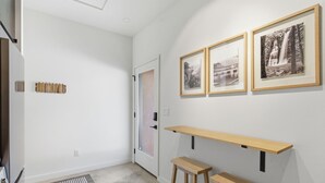 A hallway with a door, a bench, and three framed pictures on the wall. - Vista at Black Apple | On NWA Trail | Downtown (Bentonville)