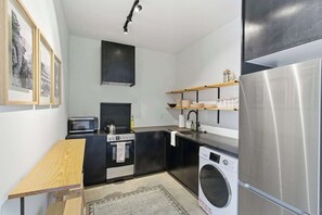 Cocina compacta equipada con microondas, estufa, fregadero y lavadora.