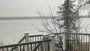 A wooden deck with a railing, a view of a body of water, and a tree. - Lakefront Retreat w/ Private Dock & Beach Access (McCall)