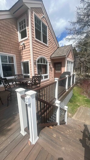 A two-story house with a deck, large windows, and a small porch area.